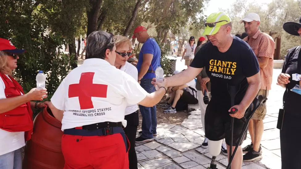 Volunteers from the Hellenic Red Cross hand out water bottles